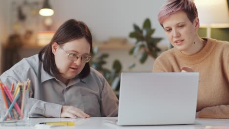 man with down syndrome learning laptop with social worker