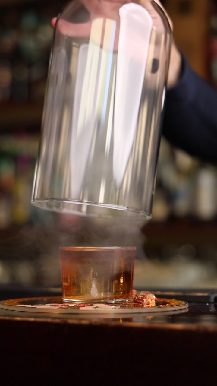 Barman che infonde un cocktail affumicato sotto una cloche di vetro