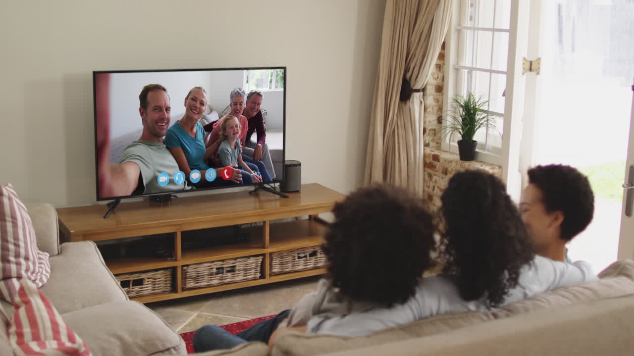 Famiglia afroamericana che fa una videochiamata in TV mentre è seduta sul divano a casa