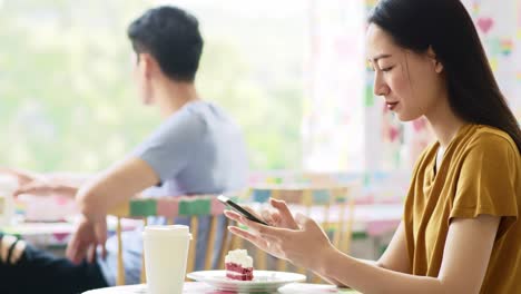 Handheld-Ansicht-Einer-Vietnamesischen-Frau,-Die-Im-Café-Ihr-Mobiltelefon-Benutzt