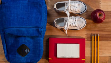 animation of black back to school text on blue circle moving over schoolbag, shoes and stationery