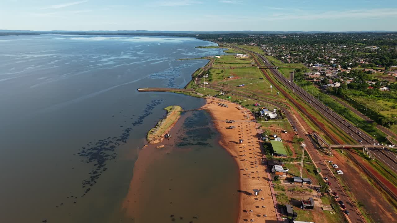 Forward drone fly over sandy coastal Balneario Costa Sur with Paraná River on the left side, Posadas, Misiones, Argentina