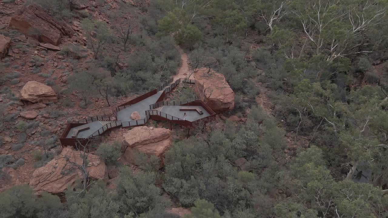 mujer ondeando en la plataforma de observación con un paisaje densamente frondoso de kings creek walk en petermann, australia