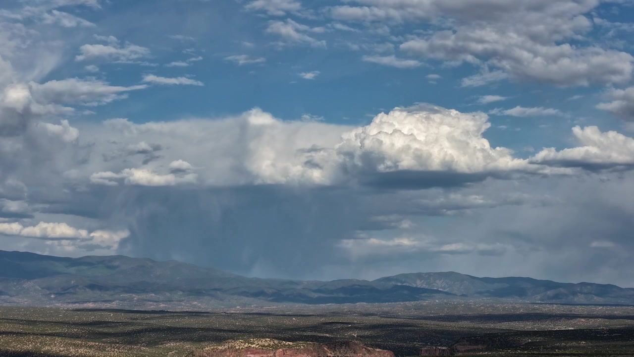 Timelapse de drone capturando uma tempestade sobre uma cordilheira. Nuvens dinâmicas se transformam enquanto luz dramática e sombras mutáveis varrem a vasta paisagem desértica