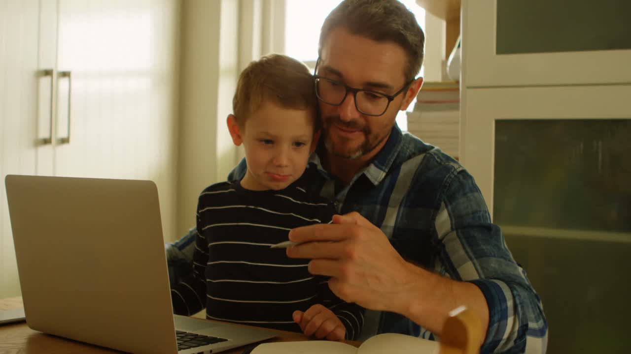 padre mostrando la pluma al hijo en la cocina 4k
