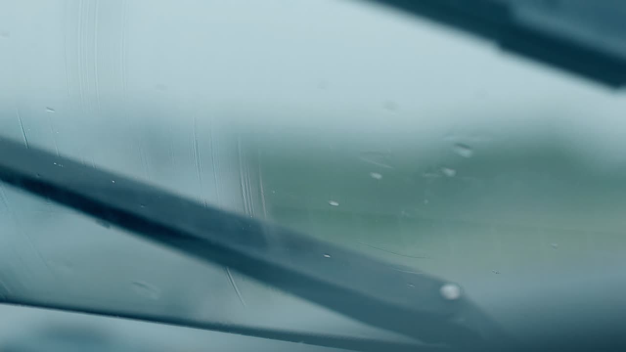 가까운 시야 검은 와이퍼가  ⁇ 은 자동차 유리에서  ⁇ 방울을 청소합니다.