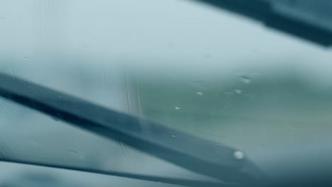 close-view-black-wiper-cleans-raindrops-from-wet-car-glass