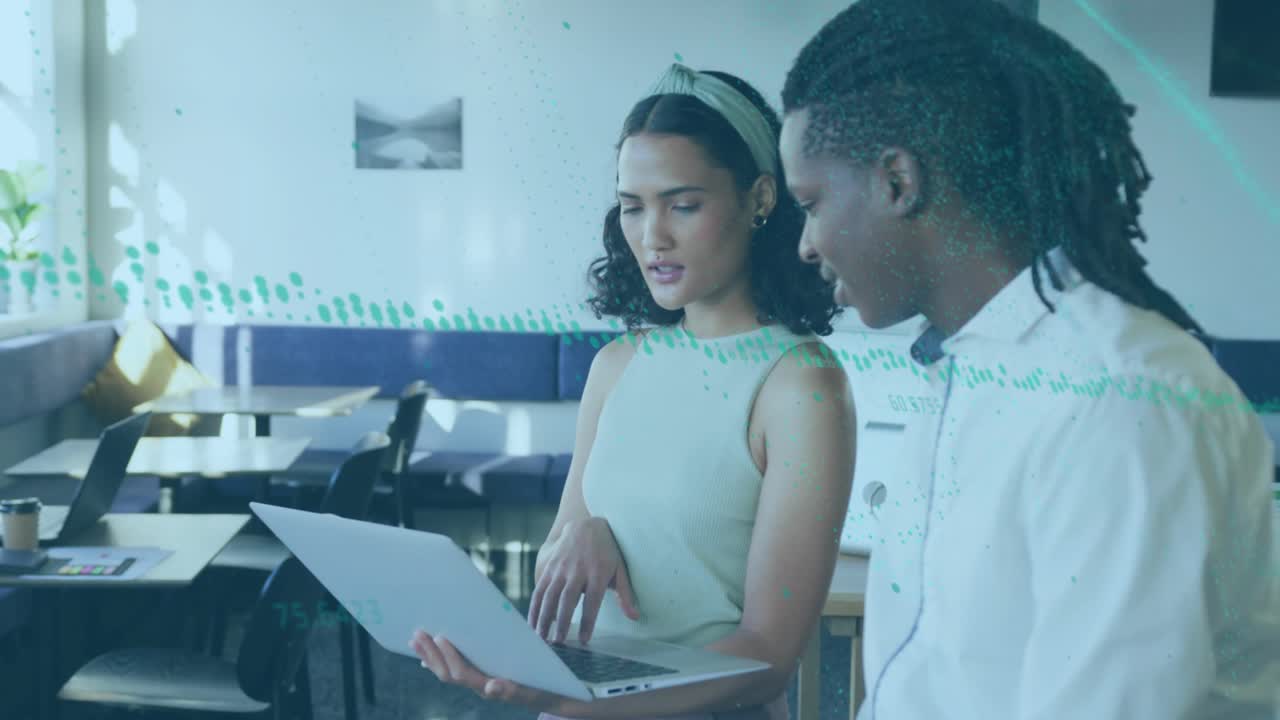 Two colleagues tapping laptop and reviewing business charts with green overlay showing analytics