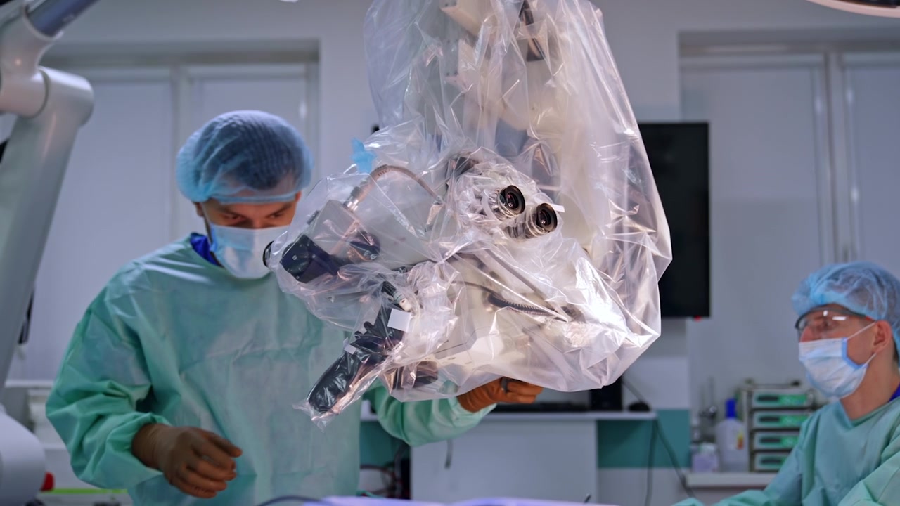 Male doctor moves the microscope hanging in surgery room. Medical equipment covered in plastic is prepared for usage at neurosurgery.
