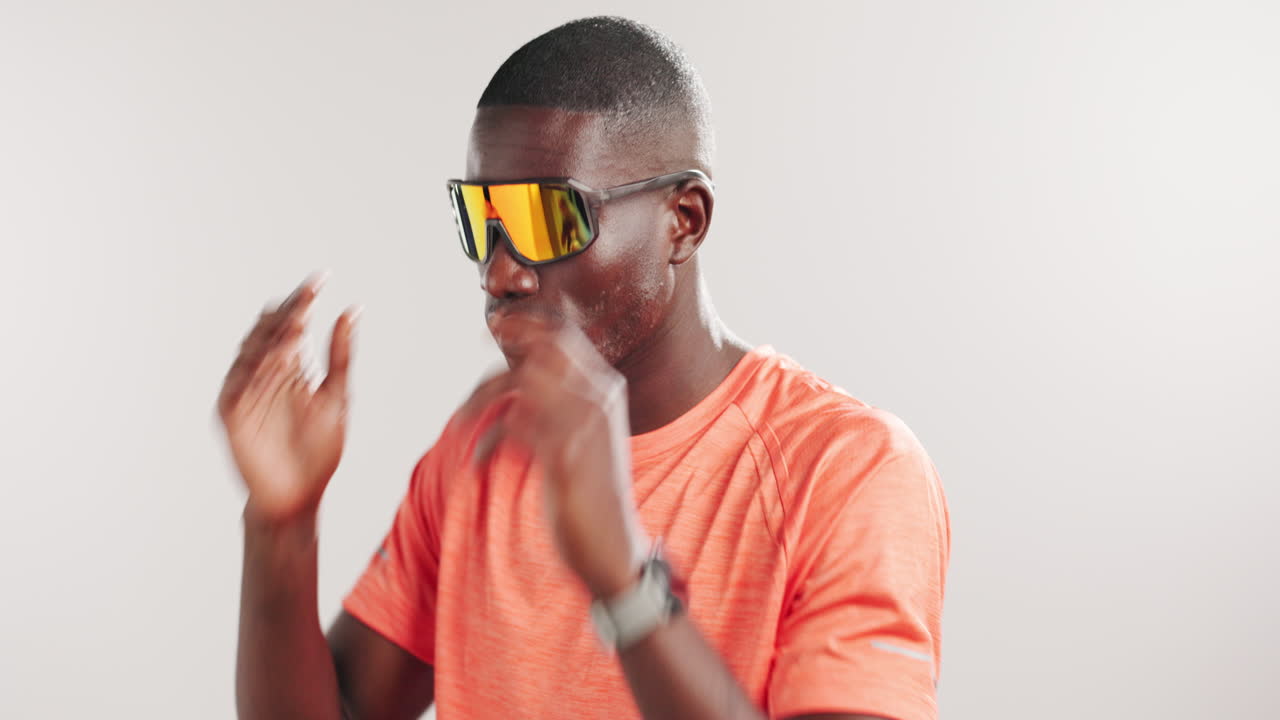 Male Athlete Puts on Sports Sunglasses and Stretches Arms in Studio