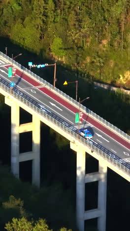 vertical drone shot following a car on bridge, driving to a tunnel in china