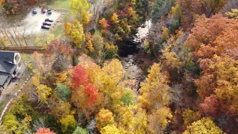 vibrant fall colors shroud a stunning flowing river aerial descending dolly