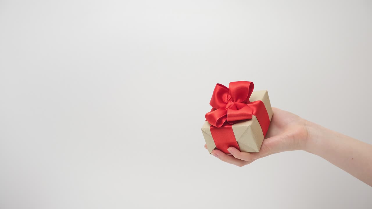 la mano de la mujer agita un regalo en un fondo claro