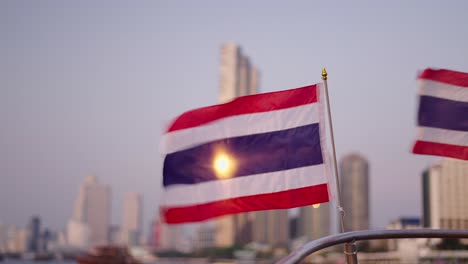 thai flag over the river city skyline at sunset