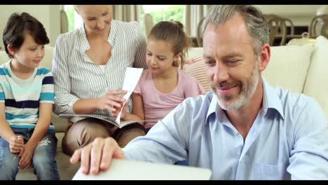 Man-smiling-while-family-watching-photo-album-together-in-background