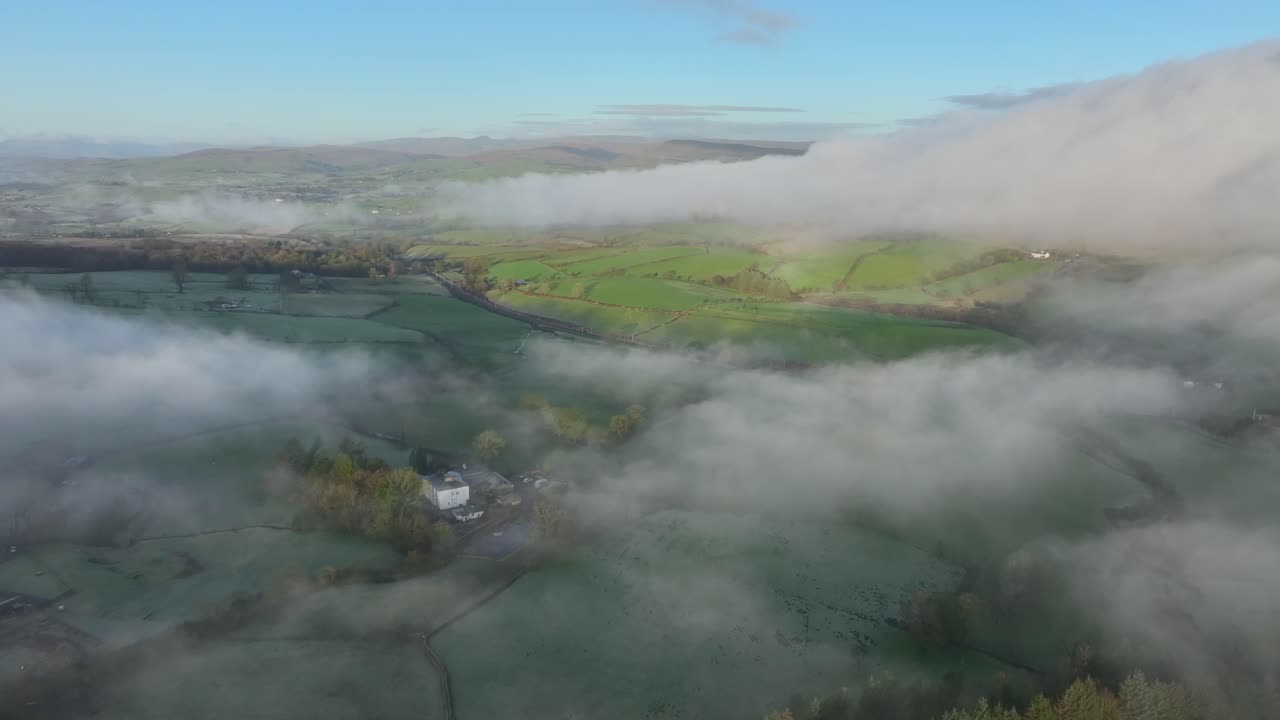 구름과 안개와 안개는 겨울의 새벽에 빛으로 빛나는 영국 시골 지역을 감싸고 있습니다.