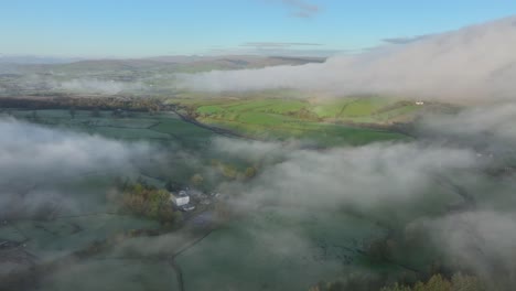 Cloud,-mist-and-fog-shrouded-English-countryside-with-sunlit-patches-at-dawn-in-winter