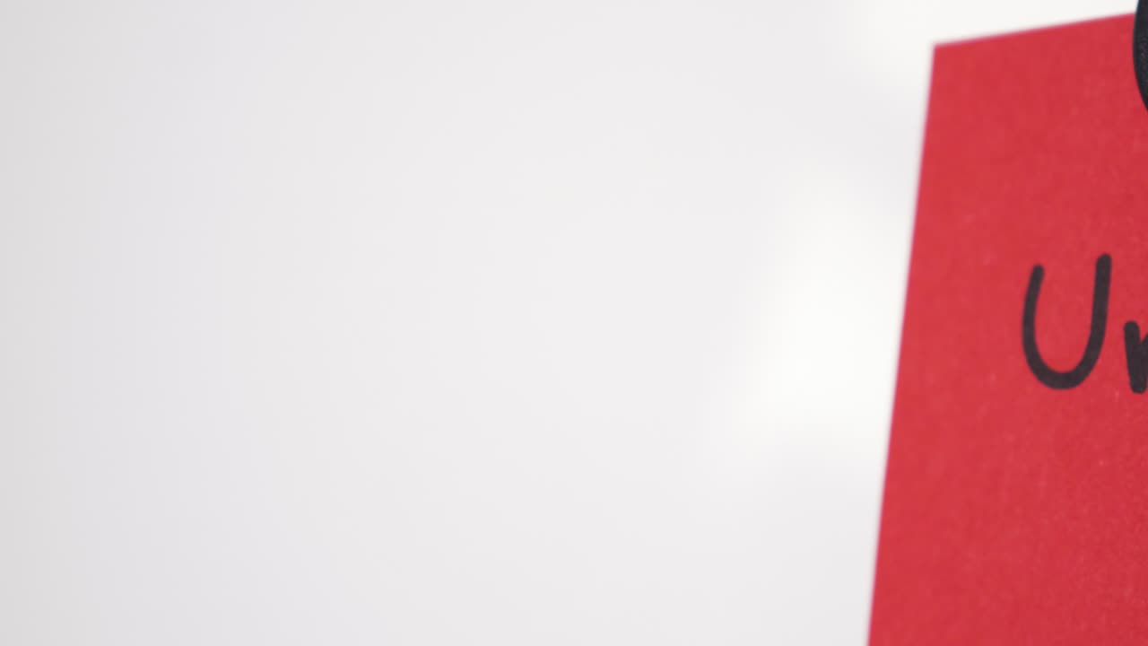 Pan reveal of Urgent text on red note held by magnet on whiteboard with selective focus