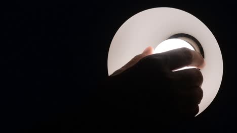 hand screwing light bulb in dark room