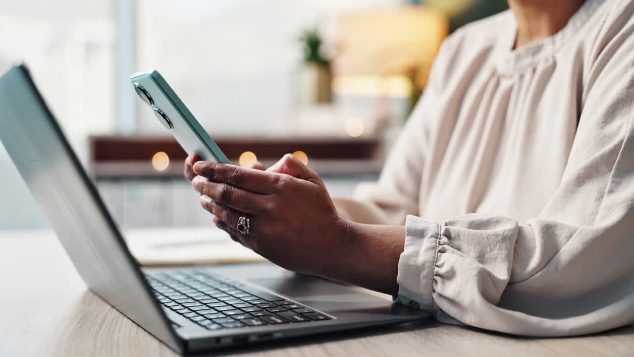 Woman using smartphone and laptop at desk