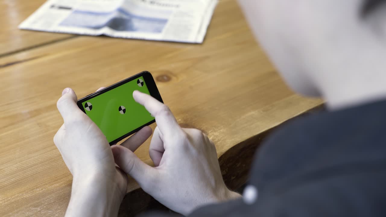 초록색 화면을 가진 스마트폰을 사용하는 사람