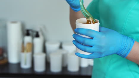 close - up of hands in rubber gloves open a jar of sugar for hair removal by sugaring