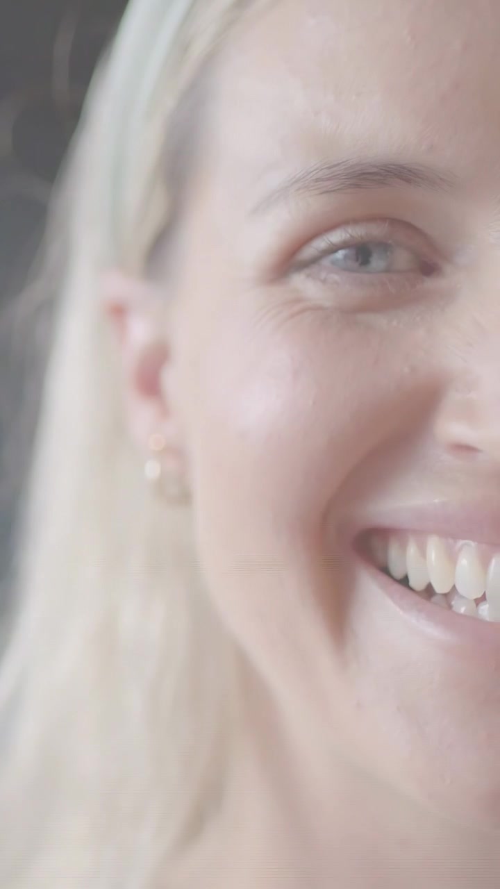 Video verticale: Donna che sorride mentre la telecamera zooma, mostrando l'occhio e l'orecchino per il marketing della bellezza.
