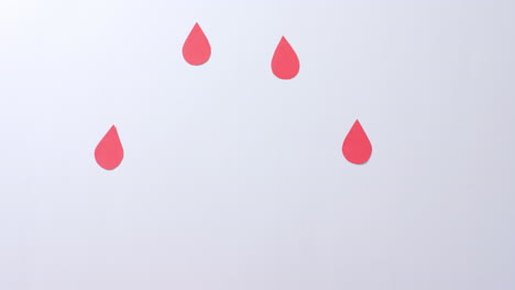 hands of caucasian woman cupping blood drop, with blood drops on white background, slow motion