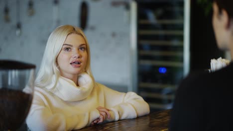 Smiling-blonde-girl-makes-order-in-coffee-shot-to-bartender-woman