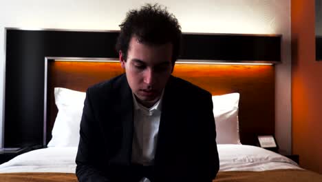 tired male business traveler sitting and falling on hotel bed