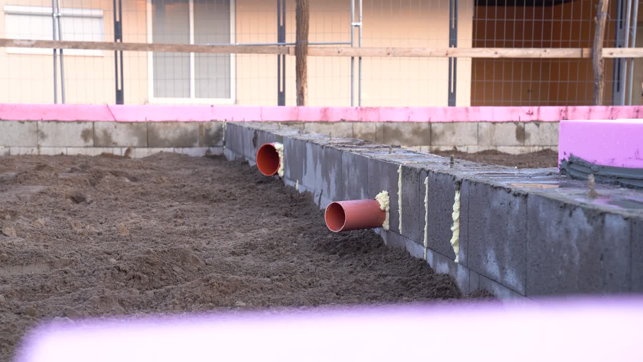 Insulated pipes installed in block foundation base at house construction site