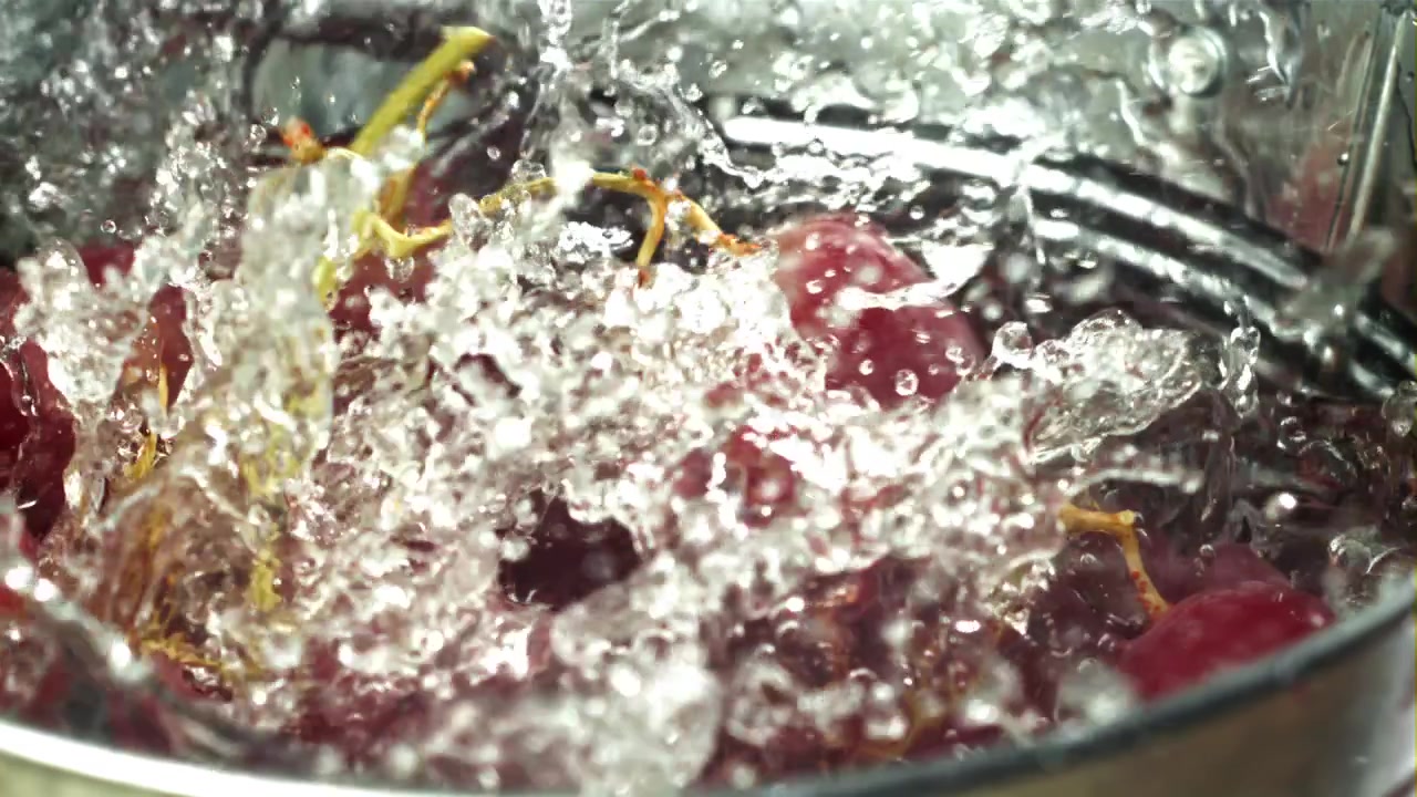 Uva rossa fresca che schizza nell'acqua al rallentatore