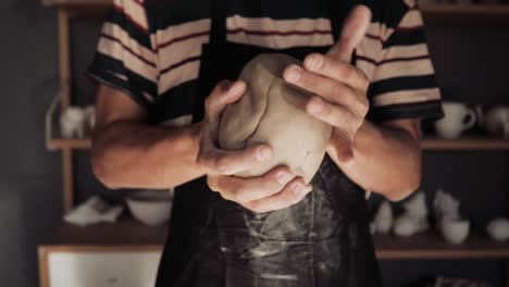 close-up of a male potter holding clay in his hands and kneading it with palm strokes.