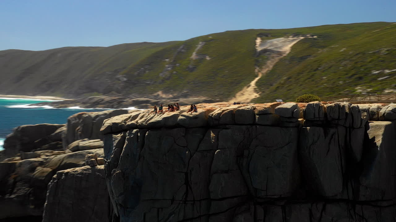 Aerial orbit, drone shot around girls on the top of the Gap lookout point, on the Coast of Sydney, sunny day, in Australia