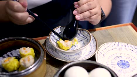 person savoring dumplings with chopsticks and spoon