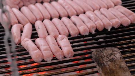 slow motion: chef grilling fresh meat sausages on big round hanging grill