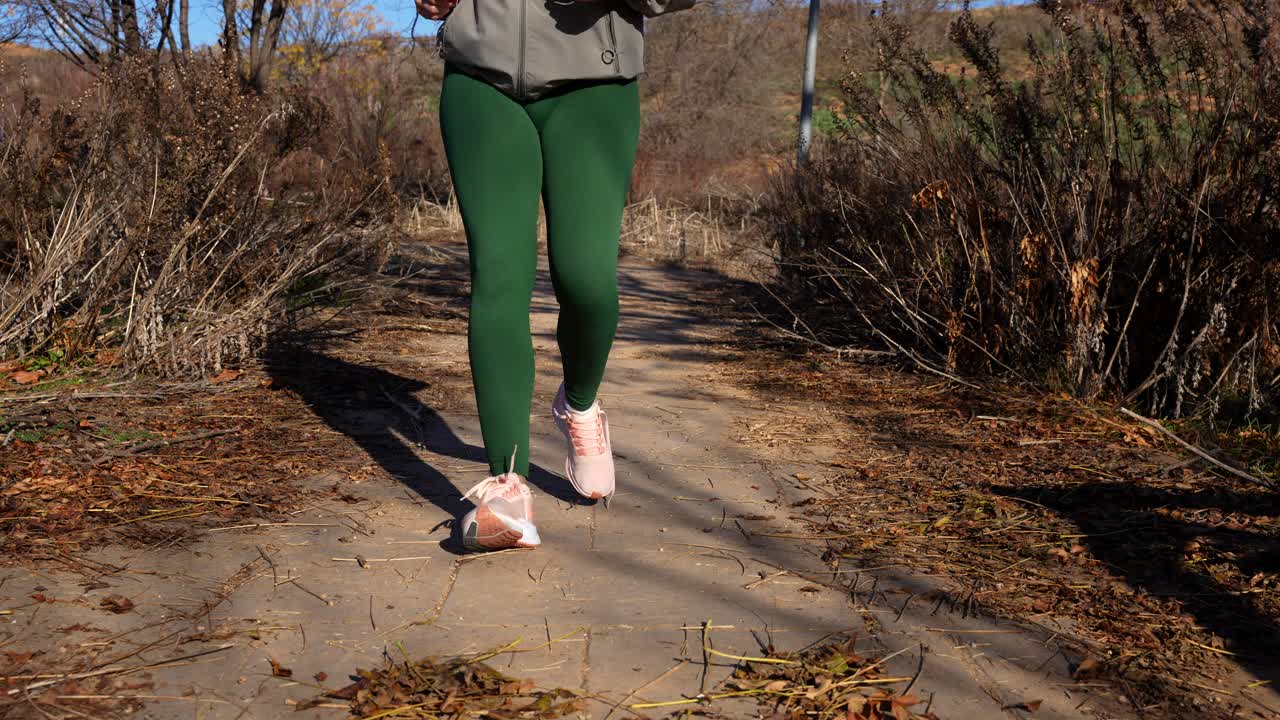 mujer haciendo una pausa en su rutina de carrera para atar los cordones de los zapatos