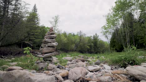 Malerische-Landschaft-Felsiges-Flussbett-Mit-Steinhaufen-Inukshuk-Cairn-In-Bewaldeter-Landschaft