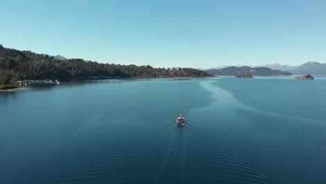 aerial: big sailboat hauling dinghy on lago nahuel huapi in patagonia