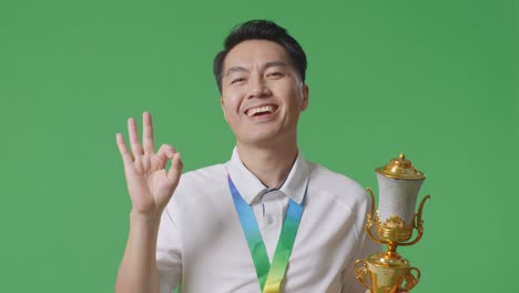 man holding a trophy and making an ok gesture