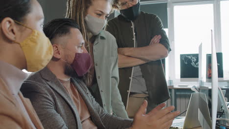 team of colleagues in face masks working on project