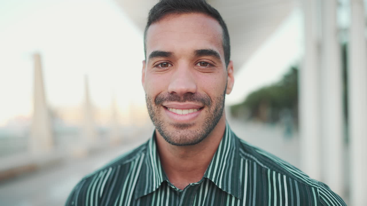 Young man smiling at the camera outdoors.