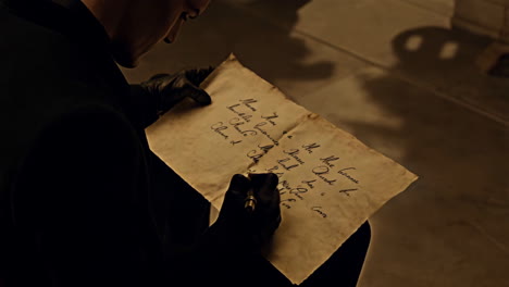 a person in gloves writing on old parchment