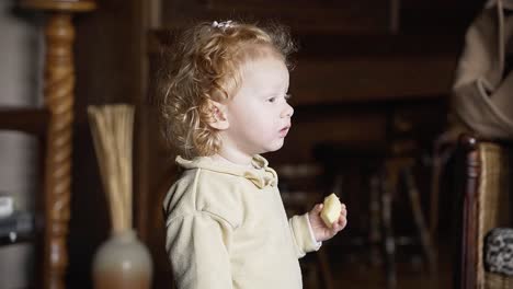 cute toddler eating a piece of an apple in grandmothers antique living room