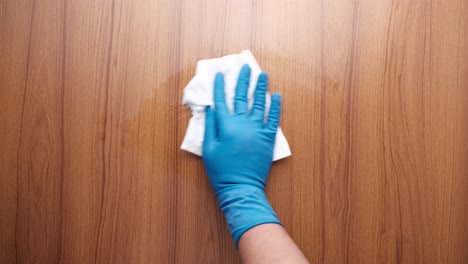 cleaning a wooden surface with a cloth and gloves