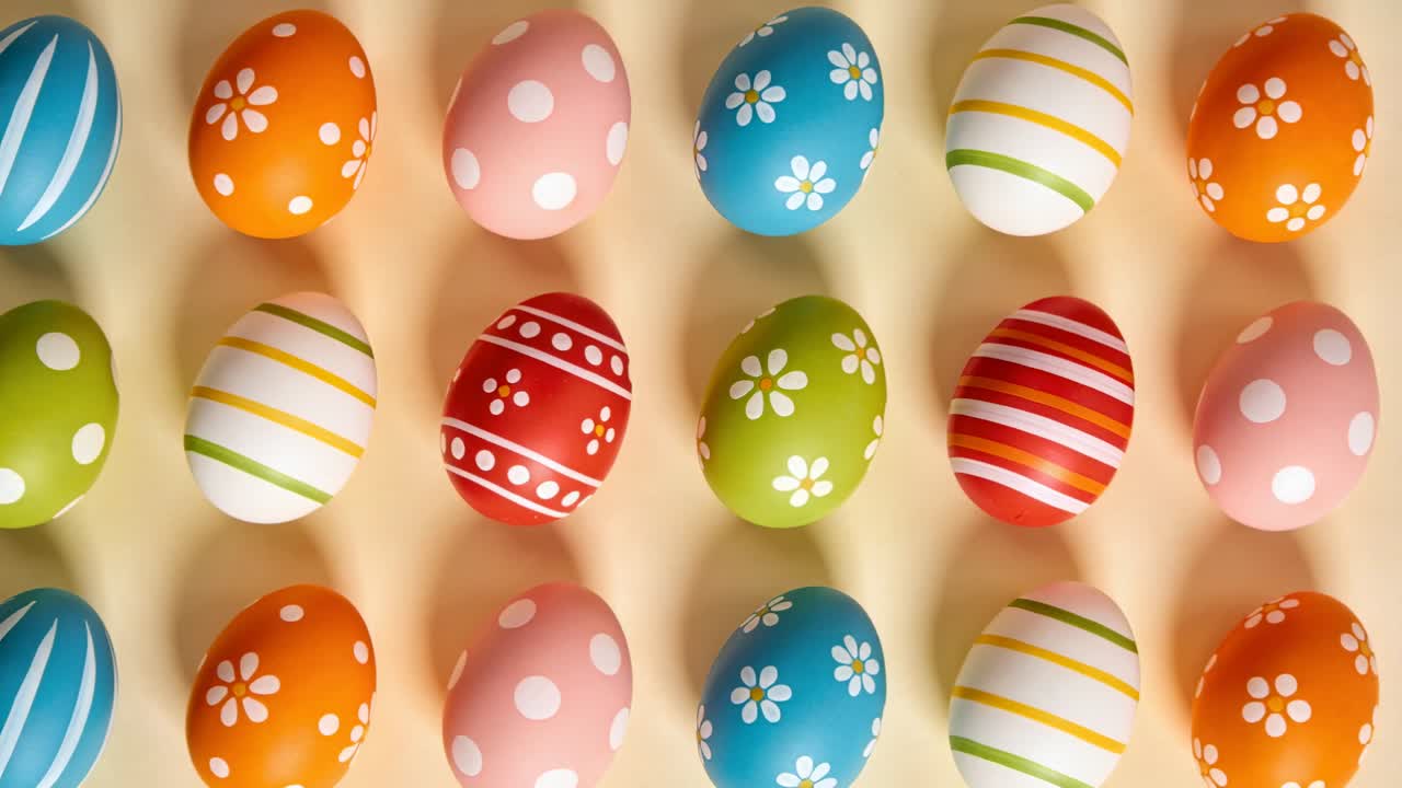 Tilting overhead camera showing decorated eggs in 5x4 grid on beige table, highlighting patterns