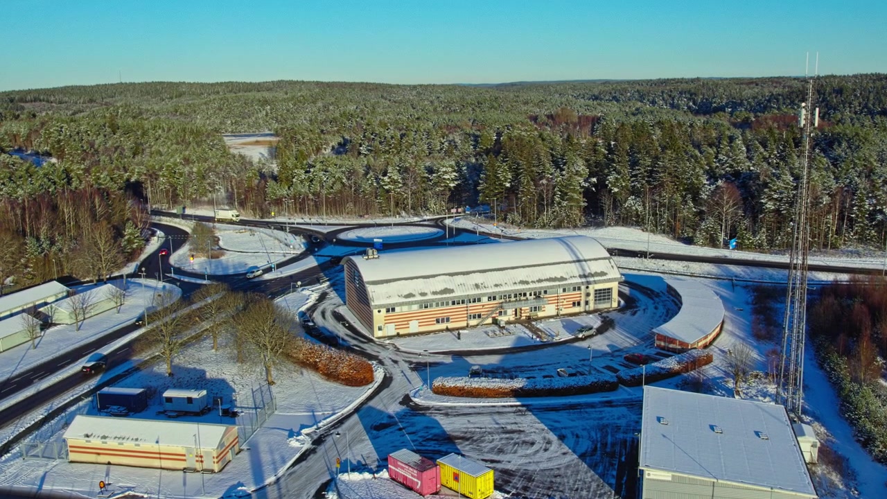 Hasičská stanice Öjersjö, Partille, Švédsko, letecký pohled během zimního dne, ukazující moderní architekturu budovy a okolní zasněženou lesní krajinu.