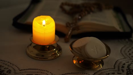 faithful puts a candle next to the communion hosts in the twilight