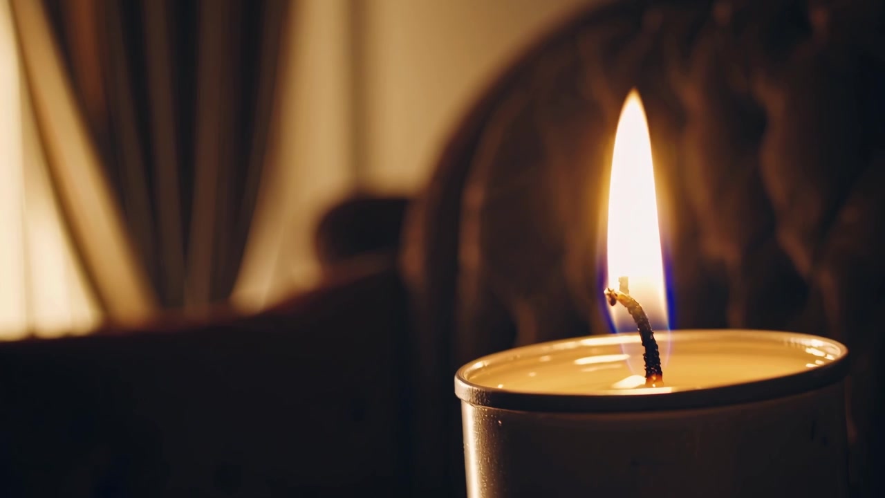 Primo piano di una fiamma di candela accesa in una stanza buia