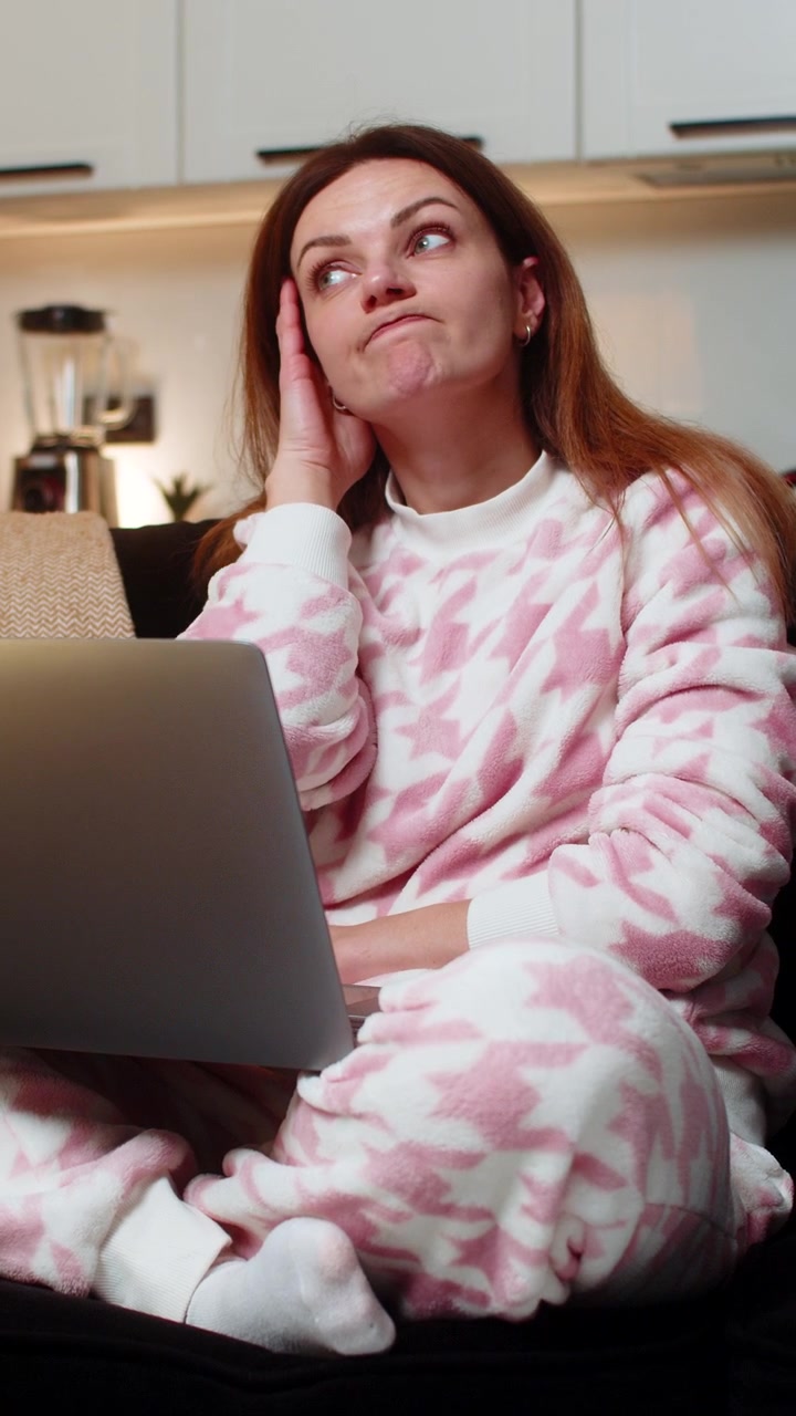 Adult woman with laptop at night deep in thought during remote work online session focused calm deep